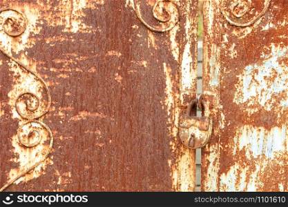 An old rusty door lock and an old metal sheet with rust texture and weathered aged peeling paint.. An old rusty lock connects a rusty gate. Rust on old metal sheet texture.