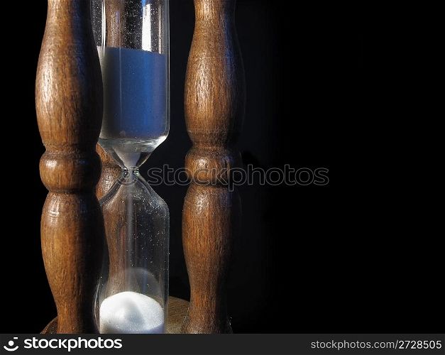 An old sandglass of wood on black background