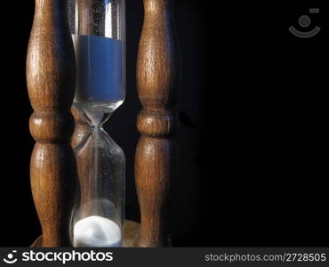 An old sandglass of wood on black background