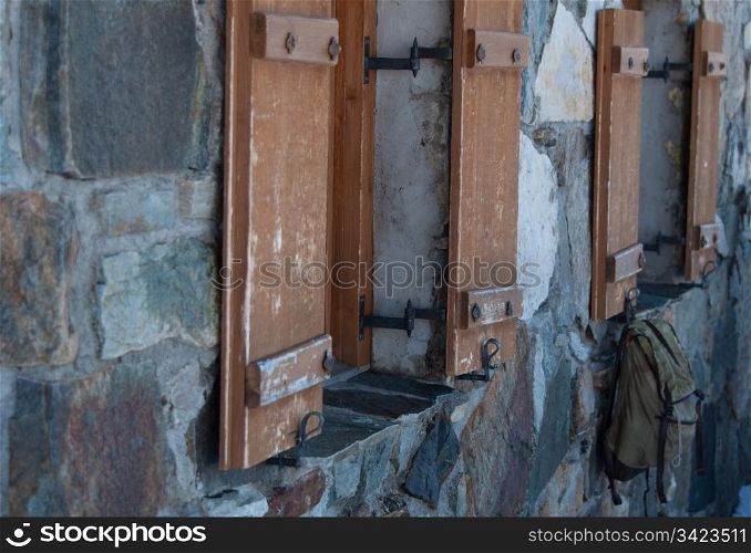An old stone house in the Austrian alps with backpack hanging from a window slide