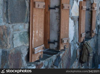 An old stone house in the Austrian alps with backpack hanging from a window slide