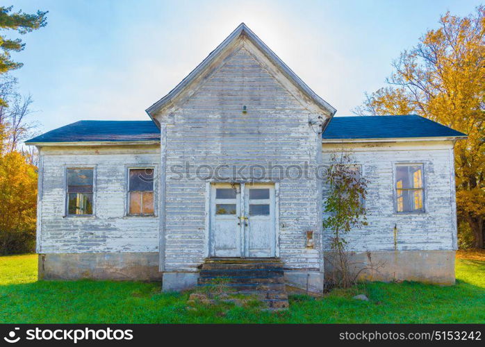 An old white abandoned farm house in the fall