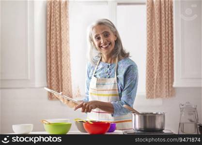 An old woman cooking with the aid of recipe.
