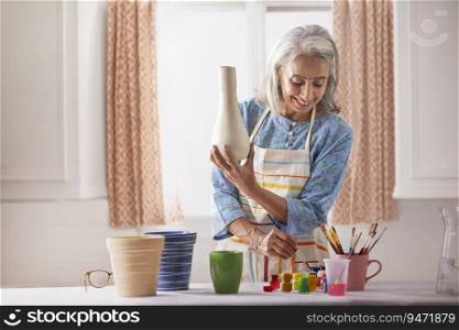 An old woman painting a vase.