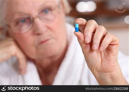 An old woman taking a pill.