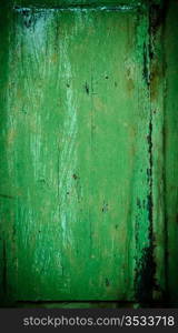An old wood window panel with cracked green paint and grunge