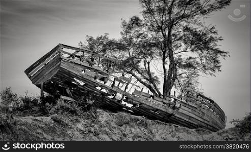 An old wooden boat washed ashore and left abandoned on mound by the Maputo Bay beach