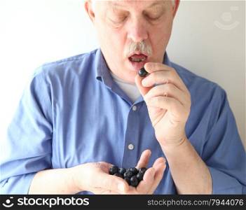 an older man eating a blueberry while holding a handful