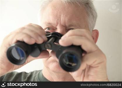 An older man holds an old pair of binoculars