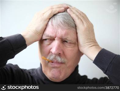 An older man holds his head while taking temperature.