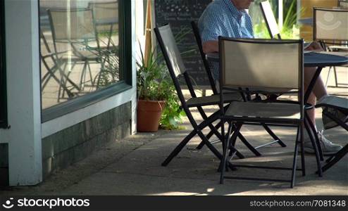 An older man sitting at a street side cafe