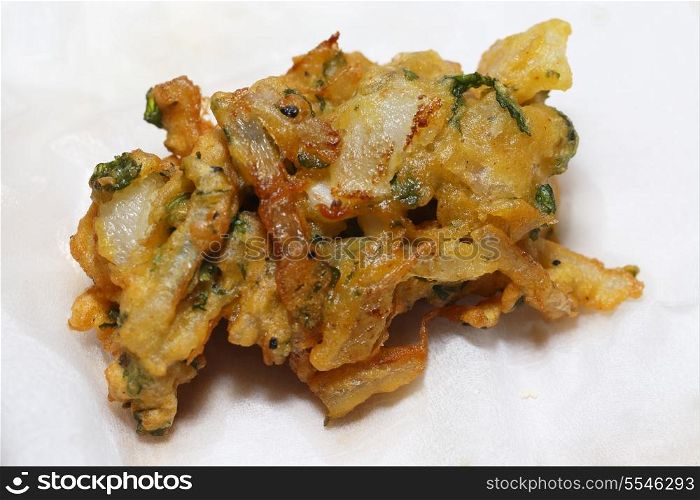 An onion bhaji, straight from the pan, draining on a sheet of kitchen paper