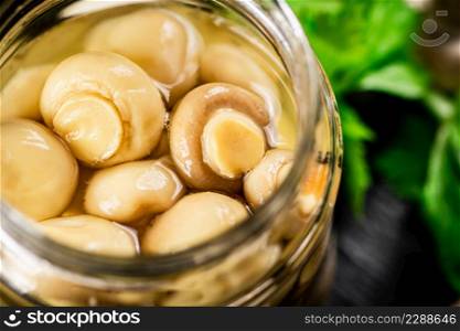 An open jar of homemade pickled mushrooms. On a black background. High quality photo. An open jar of homemade pickled mushrooms.