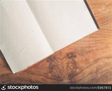 An open notepad with blank white pages on a wooden table