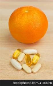 An orange and tablets either medicinal pills or nutritional vitamin supplements.