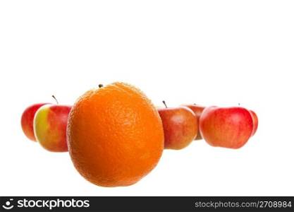 An orange stands out from a crowd of apples. Shot on white background.