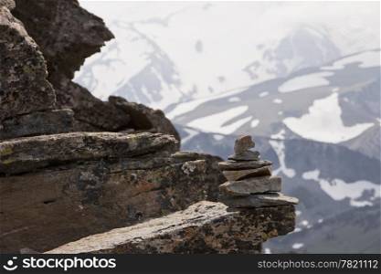 An organized pile of rocks is stacked up to form a small cairn or trail marker on a ledge high up on Mt. Rainier. In the background, the glaciers on the mountain fade into the distance.
