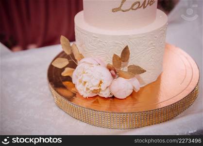 An original high wedding cake decorated with flowers and leaves.. Stylish wedding cake with leaves 3814.