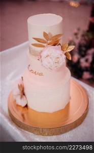 An original high wedding cake decorated with flowers and leaves.. Stylish wedding cake with leaves 3816.