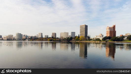 An overcast sky is reflected in the smooth water of Lake Merritt in front of Oakland