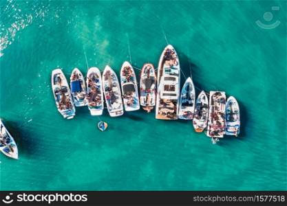 An overhead aerial drone shot of different sized boats docked close to each other near the pier. Overhead aerial drone shot of different sized boats docked close to each other near the pier