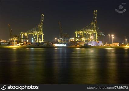 An overview of the Rotterdam Container harbor, with its huge cranes, stacked containers and industrial activity at night. Business continues 24/7