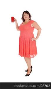 An overweight woman in a red dress standing in profile with a necklaceand holding a red coffee mug, isolated for white background