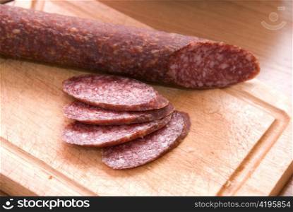 An salami with sliced pieces at table