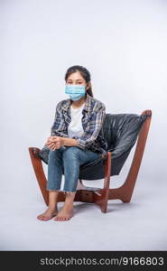 An uncomfortable woman sitting on a chair and wearing a mask