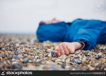 An unconscious woman is lying on a shingle beach