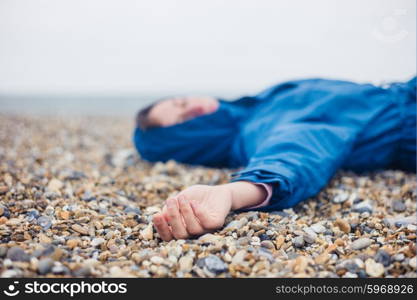 An unconscious woman is lying on a shingle beach