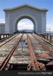 An unused boat launch and building with an arch on a San Francisco wharf. The railway tracks were used to run boats into the harbor.