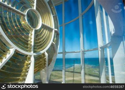 An up close view of the light of the Cape Agulhas lightouse with a view of the ocean in the background.
