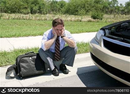 An upset businessman on the side of the road with his broken down car wating for the auto club.