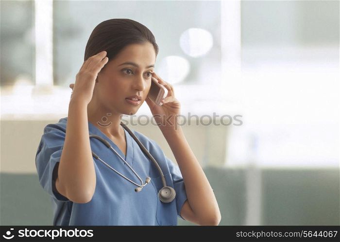 An upset young surgeon using cell phone in hospital