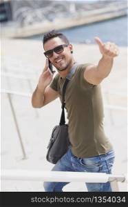 An urban man using a phone on the street and showing OK gesture