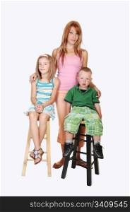An young family, a mother with her two kids, an seven year girl and athree year boy sitting on chairs in the studio for white background.