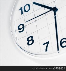 Analog wall clock, narrow focus on number nine, tinted black and white image
