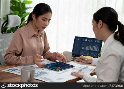 Analyst team colleague discuss financial data on digital dashboard, analyzing charts graph display on laptop and tablet screen. Modern office use business intelligence to plan marketing. Enthusiastic. Analyst team colleague discuss financial data on digital dashboard. Enthusiastic