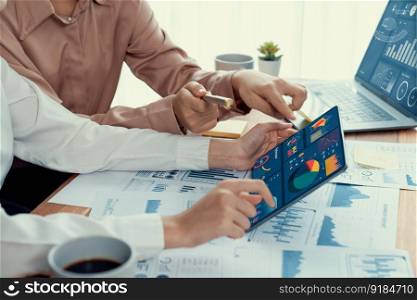 Analyst team colleague discuss financial data on digital dashboard, analyzing charts graph display on laptop and tablet screen. Modern office use business intelligence to plan marketing. Enthusiastic. Analyst team colleague discuss financial data on digital dashboard. Enthusiastic