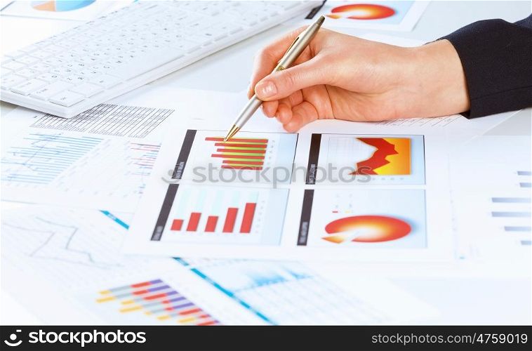 Analyzing report. Close up of male hand holding pen and pointing at graphs