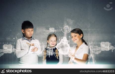 Anatomy lesson. Young teacher and her pupils examining hologram of human heart