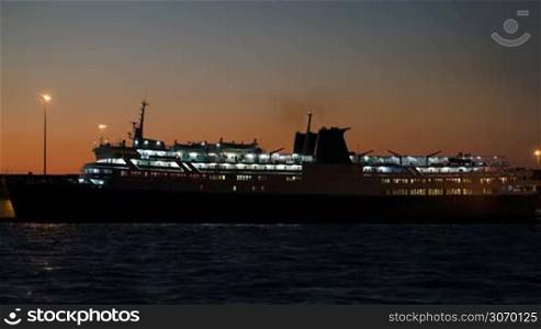 Anchored cruise ship illuminated brightly in late evening