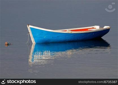 Anchored wooden fishing boat with reflection in water