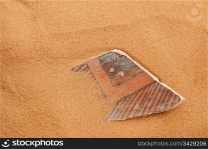 ancient Anasazi pottery shard buried in red desert sand
