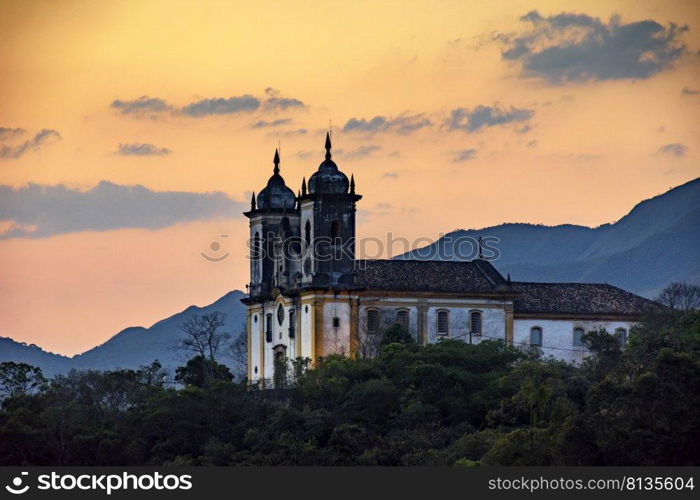 Ancient and historic church on top of the hill during sunset in the city of Ouro Preto in Minas Gerais, Brazil with the mountains behind. Ancient and historic church on top of the hill during sunset