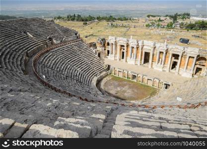 Ancient antique amphitheater in the city of Hierapolis in Turkey. Steps and antique statues with columns in the amphitheater. Ancient antique amphitheater in city of Hierapolis in Turkey. Steps and antique statues with columns in the amphitheater