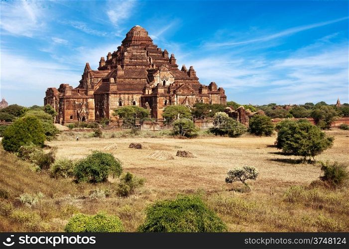 Ancient architecture of old Buddhist Temples at Bagan Kingdom, Myanmar (Burma). Dhammayan Gyi Pagoda, the biggest at Bagan with field in a front under blue sky