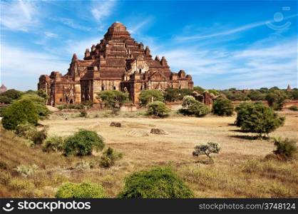 Ancient architecture of old Buddhist Temples at Bagan Kingdom, Myanmar (Burma). Dhammayan Gyi Pagoda, the biggest at Bagan with field in a front under blue sky