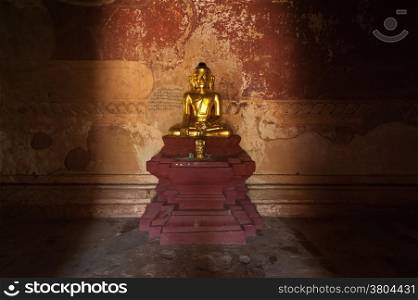 Ancient architecture of old Buddhist Temples at Bagan Kingdom, Myanmar (Burma). Golden Buddha statue inside one of pagoda ruins